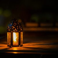 A glowing lantern with crescent motifs creates a warm ambiance for Ramadan or Eid.